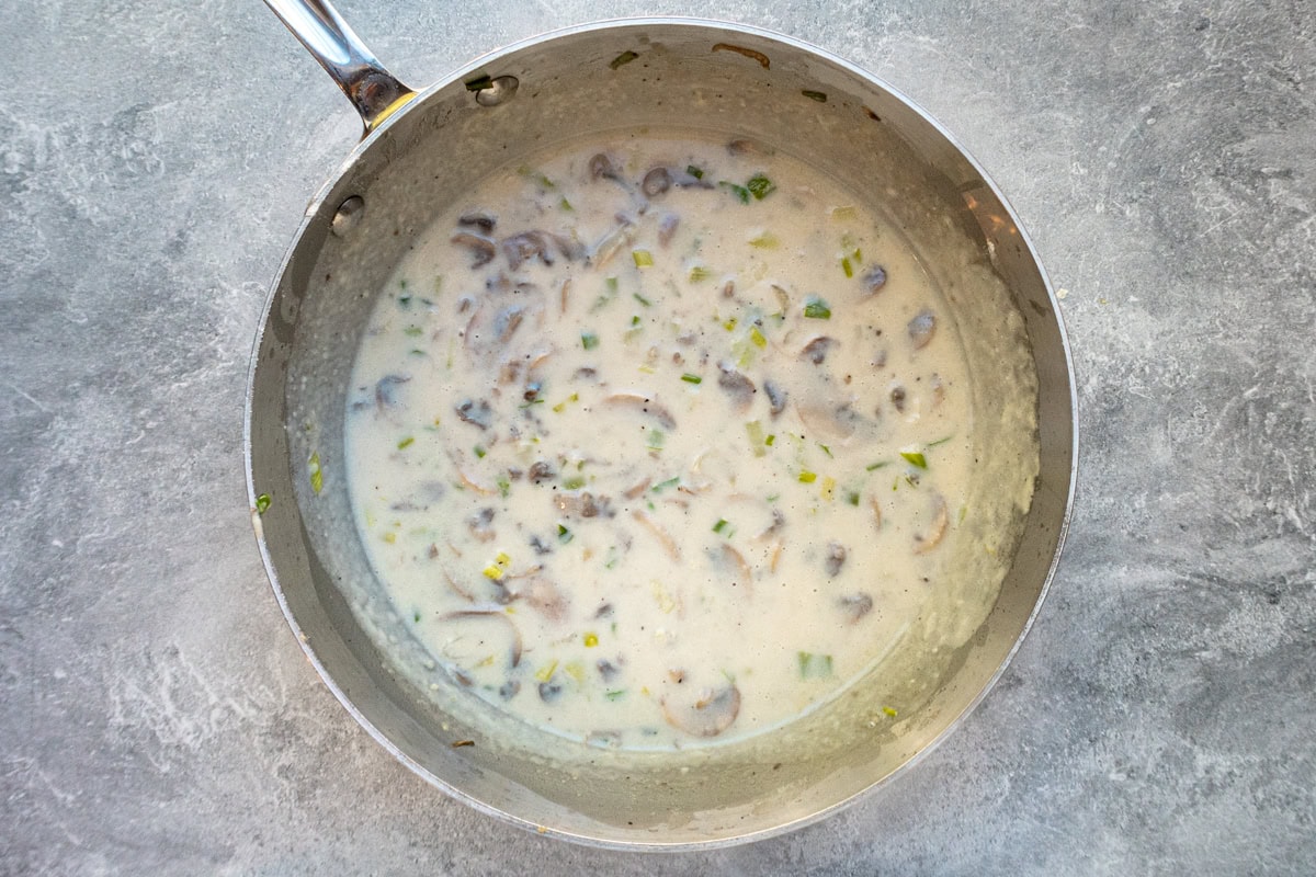 Creamy mushroom and green onion sauce mixture in a skillet.