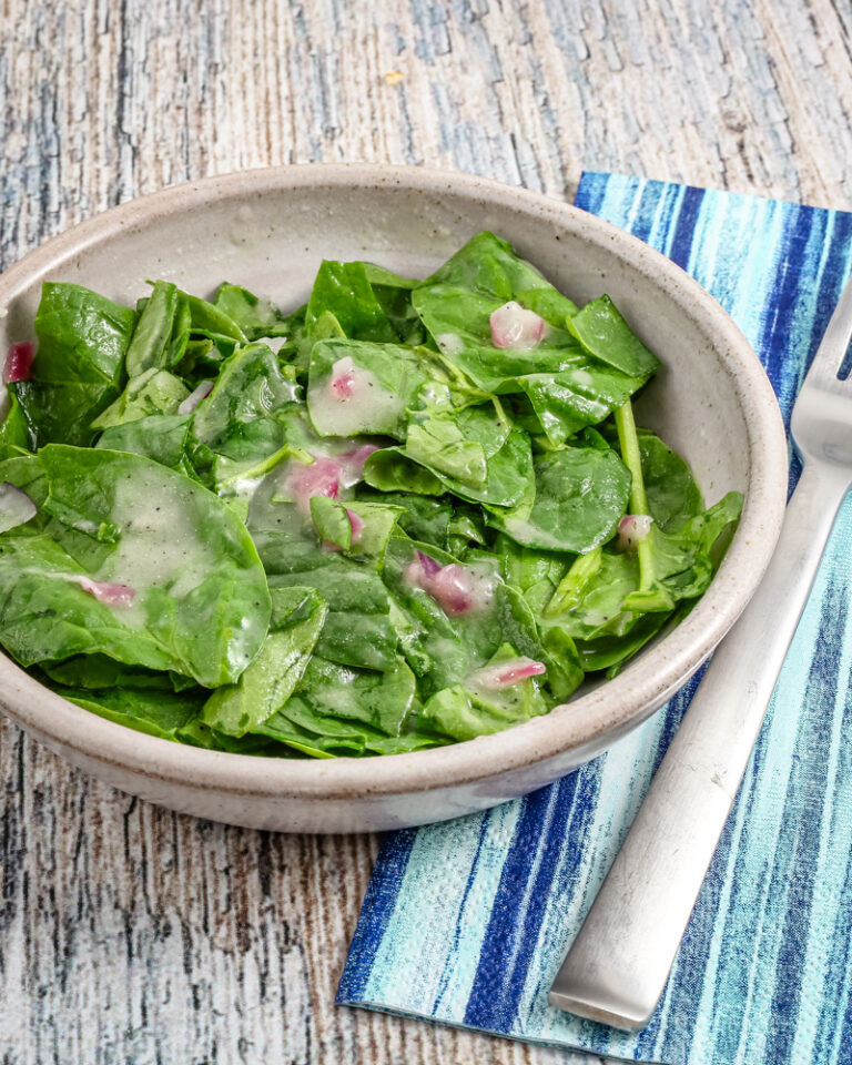 A serving of wilted spinach salad in a bowl