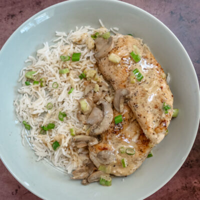 Apple brandy chicken on a bed of rice with mushrooms and green onions