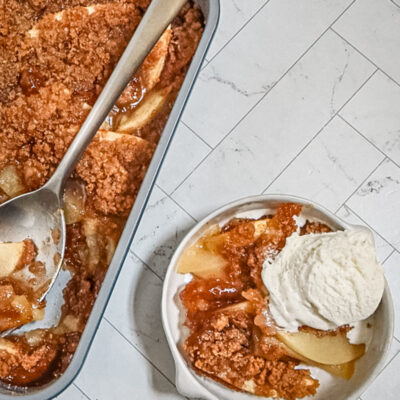 Apple betty in the baking pan with a serving beside it.