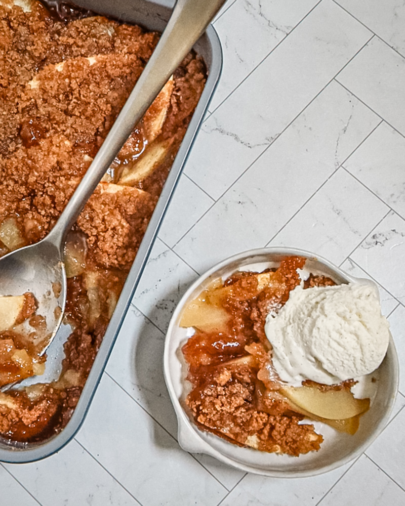 Apple betty in the baking pan with a serving beside it.