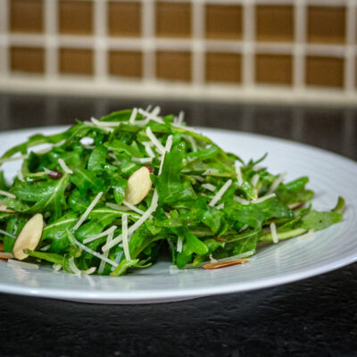 A simple arugula salad with sliced almonds on a plate