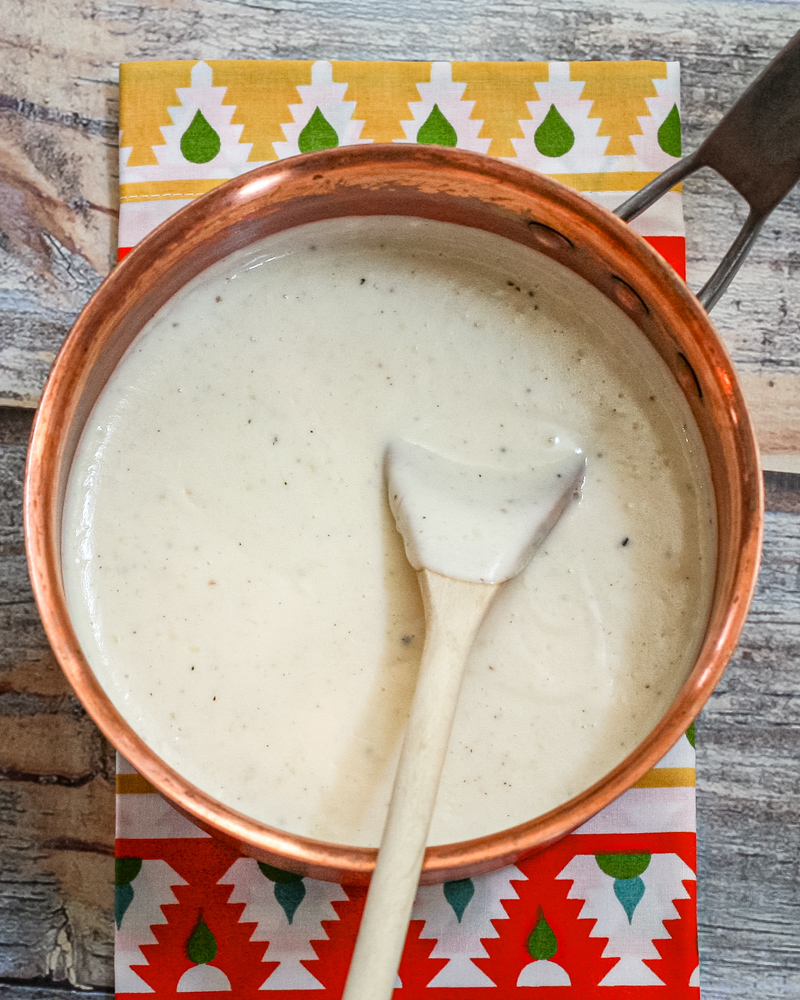a basic white sauce in a copper saucepan