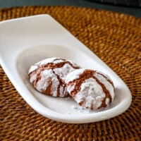 Chocolate crinkle cookies on a small serving plate.