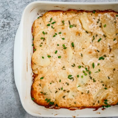 Baking dish with scalloped potatoes ganished with chives.