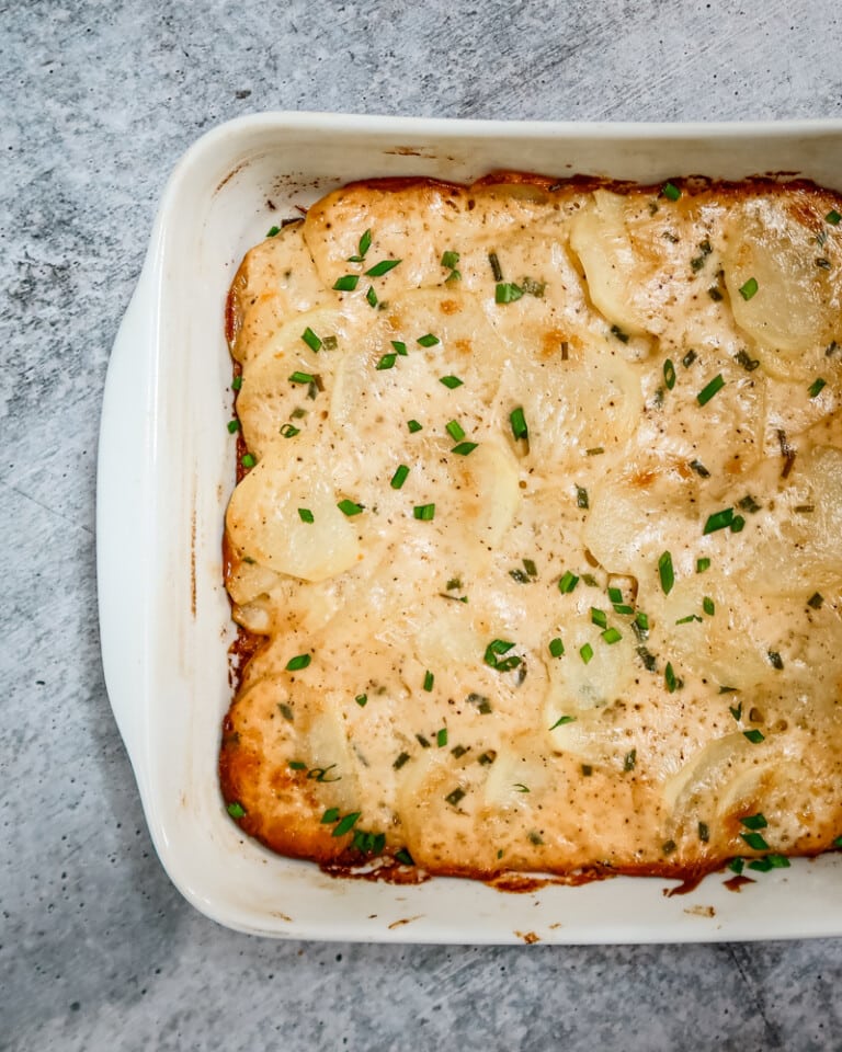 Baking dish with scalloped potatoes ganished with chives.