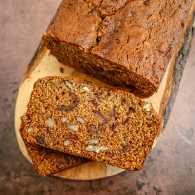 A loaf of date nut bread on a wood slab, sliced