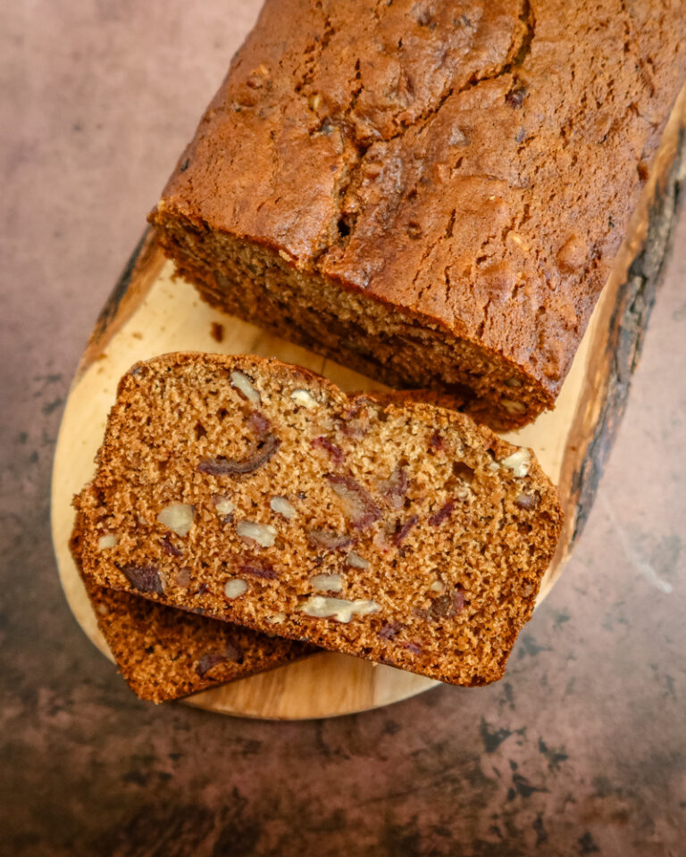 A loaf of date nut bread on a wood slab, sliced