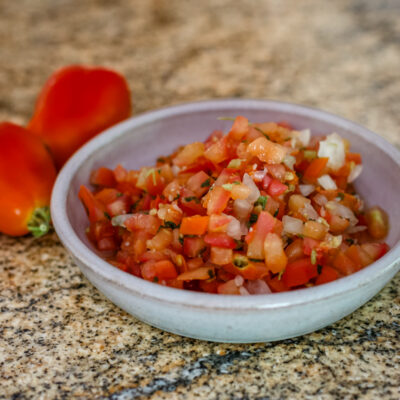 A small bowl of tomato salsa with chile peppers