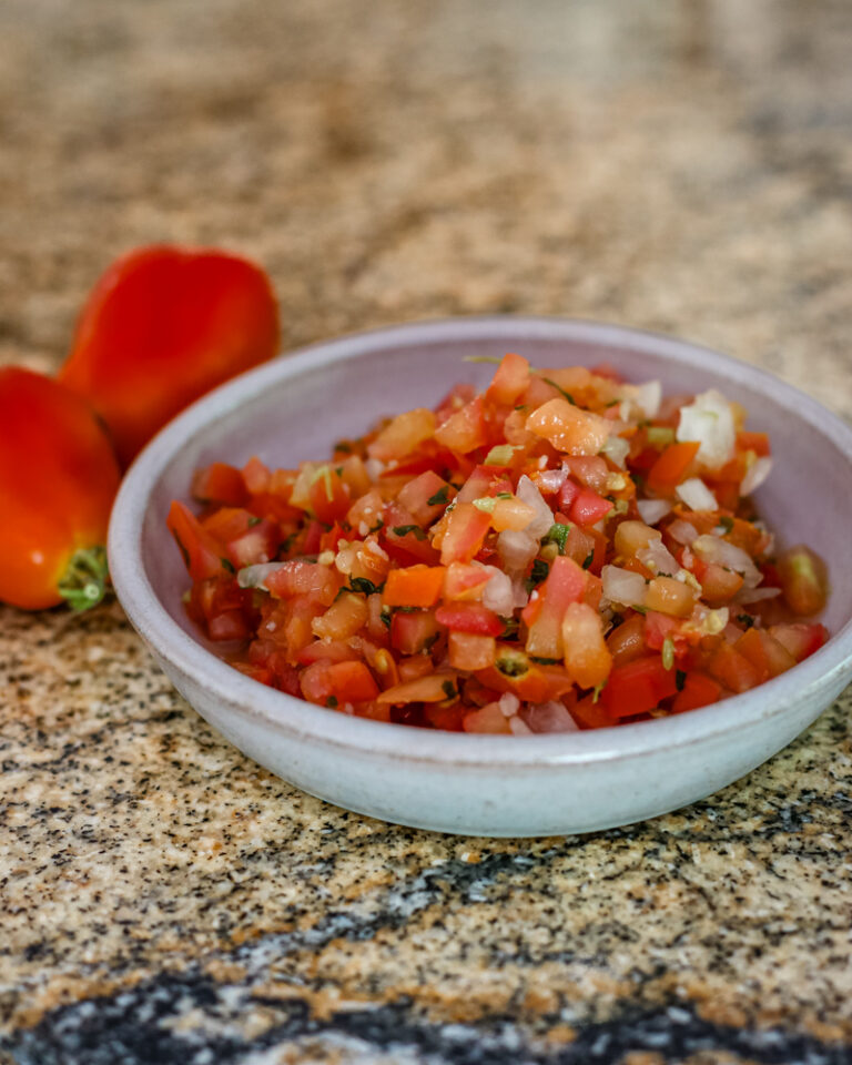 A small bowl of tomato salsa with chile peppers