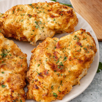 Fried chicken breasts on a plate with parsley.