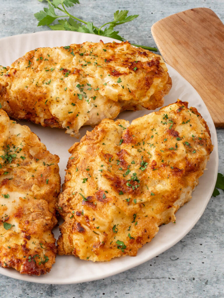 Fried chicken breasts on a plate with parsley.