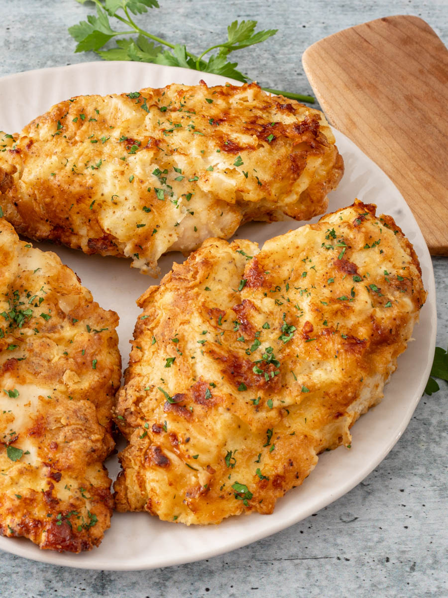 Fried chicken breasts on a plate with parsley.