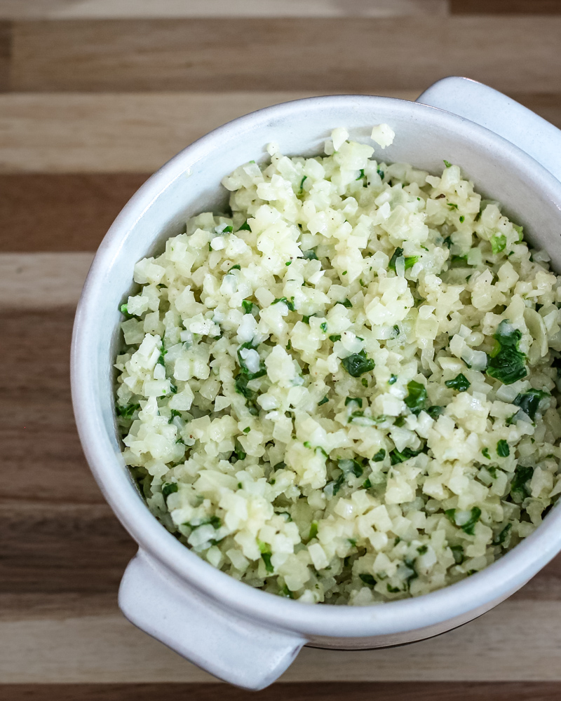 A bowl of cauliflower rice with garlic, parmesan cheese, and parsley
