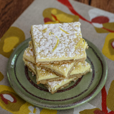 Lemon bars stacked on a plate.