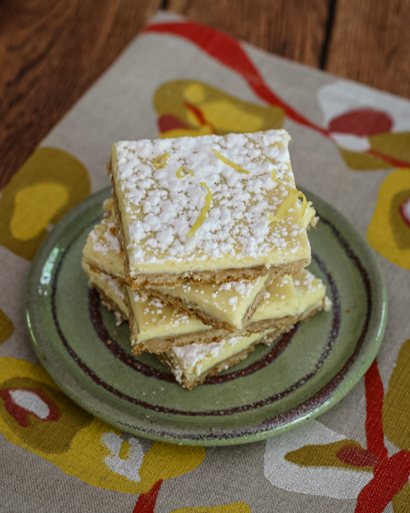 Lemon bars stacked on a plate.