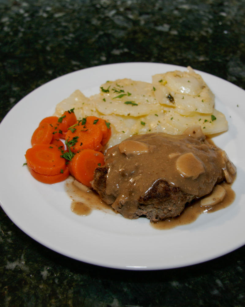 Salisbury steaks on a plate with scalloped potatoes and carrots