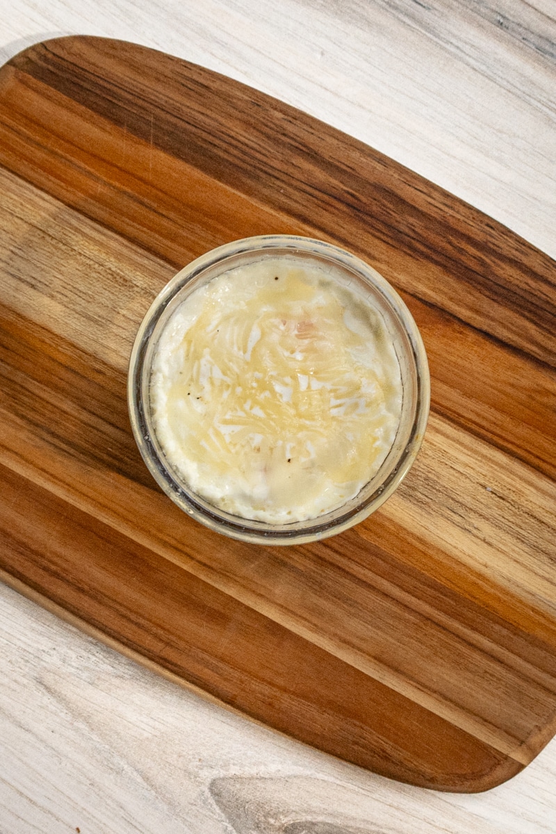 Shirred eggs baked in a glass ramekin with cheese topping.