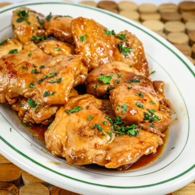 chicken thighs on a platter with sweet-spicy sauce and cilantro garnish