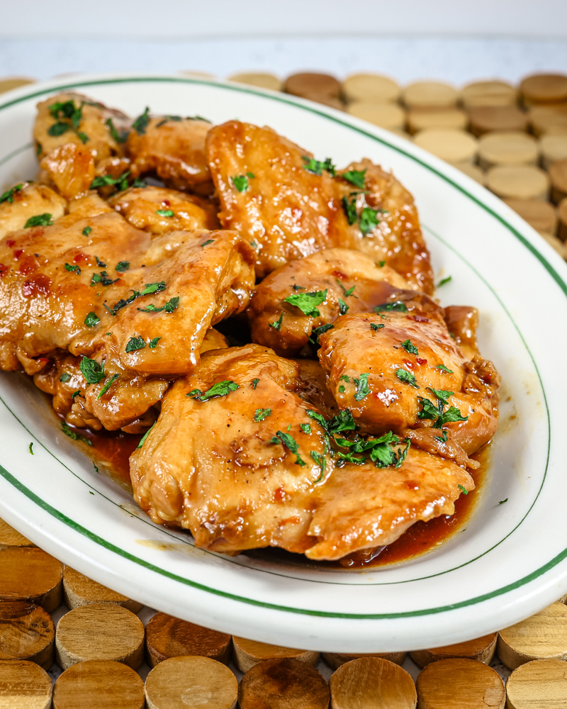 chicken thighs on a platter with sweet-spicy sauce and cilantro garnish