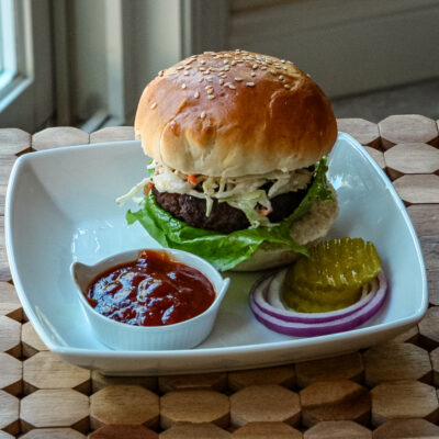 texas burger on a plate with coleslaw topping and bbq sauce