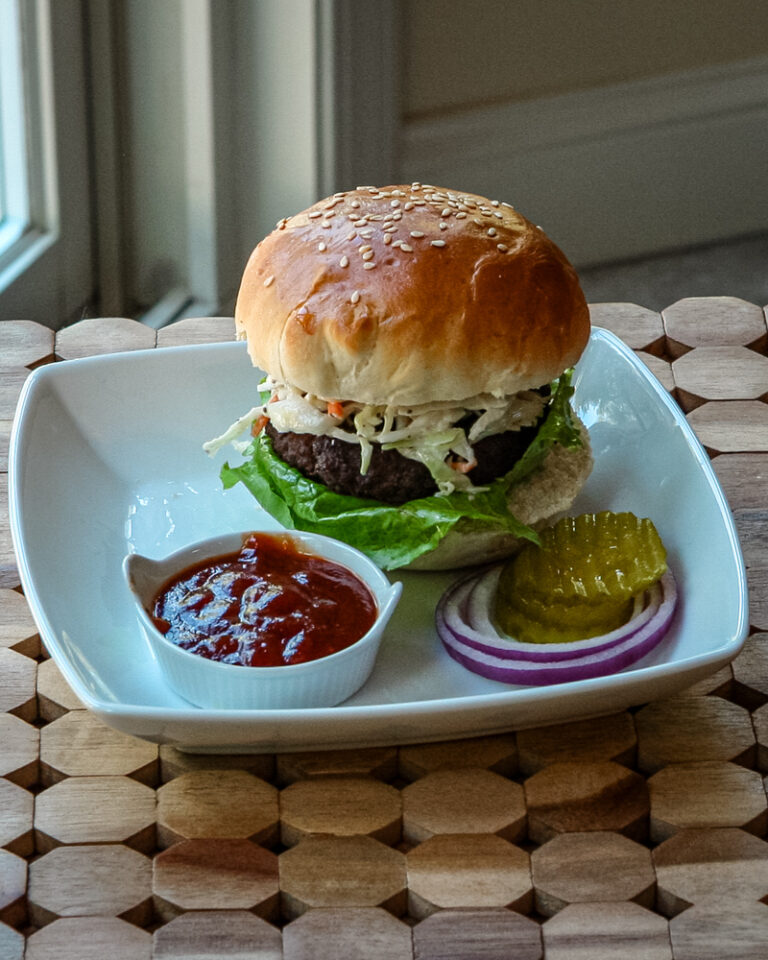 texas burger on a plate with coleslaw topping and bbq sauce