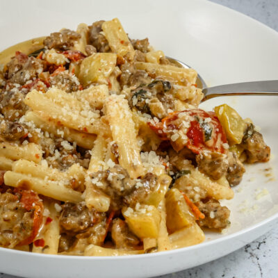 Tuscan pasta in a bowl with italian sausage, sun dried tomatoes, and zucchini
