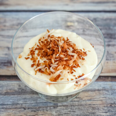 Homemade vanilla pudding in a glass dessert dish with toasted coconut