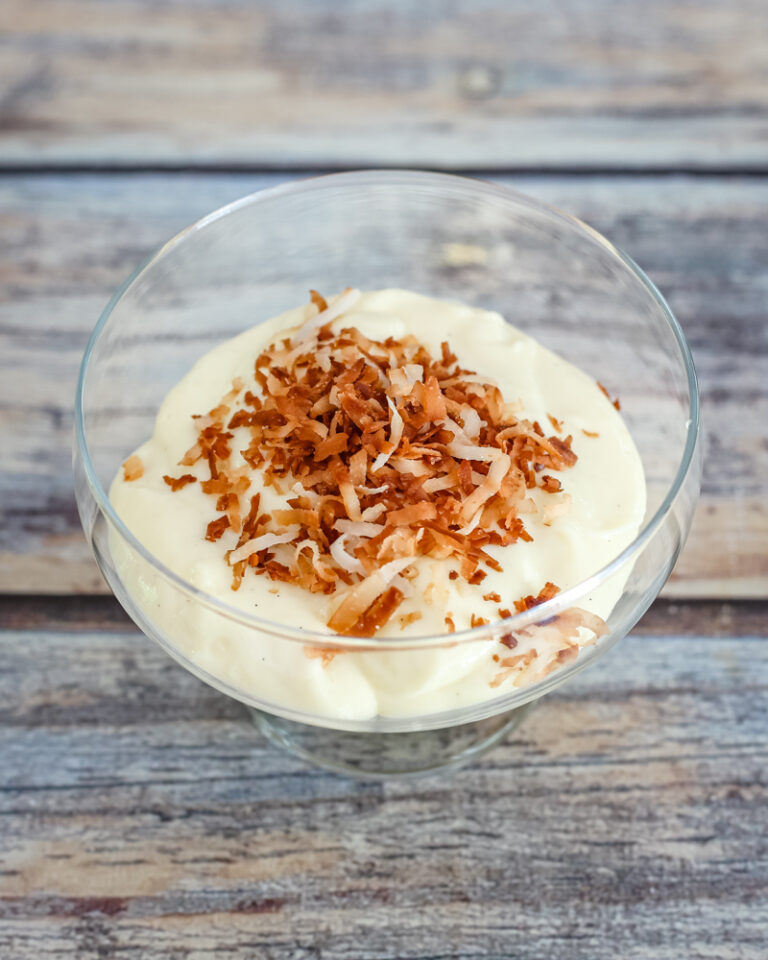 Homemade vanilla pudding in a glass dessert dish with toasted coconut