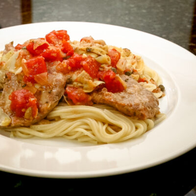 veal cutlets with tomatoes and artichokes on pasta