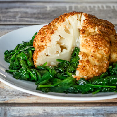 whole roasted cauliflower sliced, on a plate