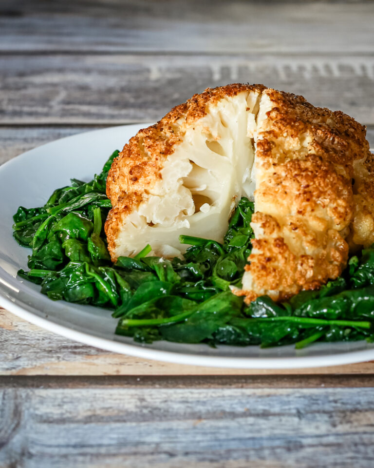 whole roasted cauliflower sliced, on a plate