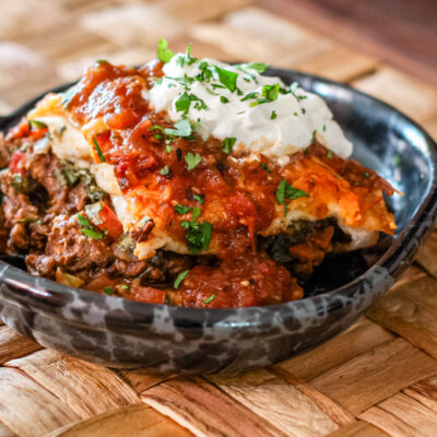 A serving of burrito casserole with sour cream.