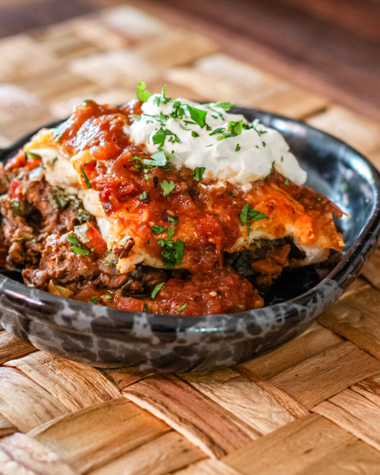 A serving of burrito casserole with sour cream.