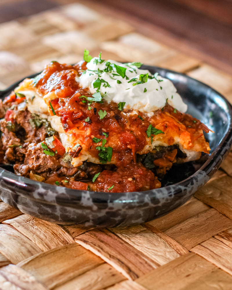 A serving of burrito casserole with sour cream.