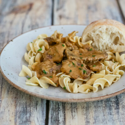 A plate of beef stroganoff on noodles.