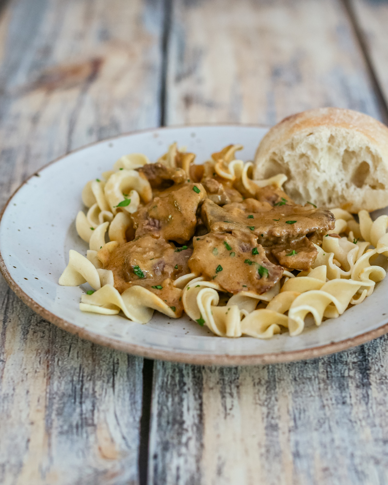 A plate of beef stroganoff on noodles.