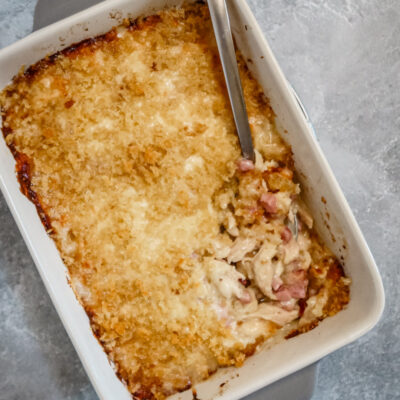 A chicken cordon bleu casserole in the baking dish with spoon.
