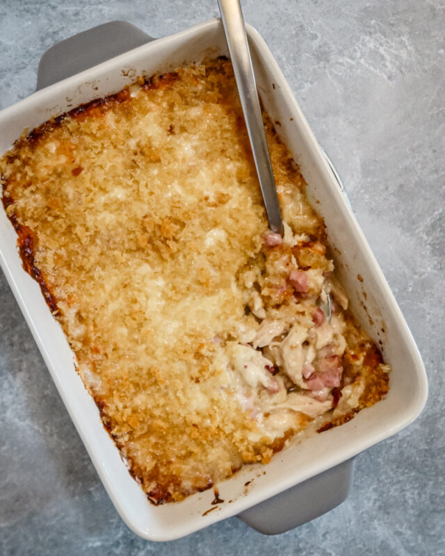 A chicken cordon bleu casserole in the baking dish with spoon.