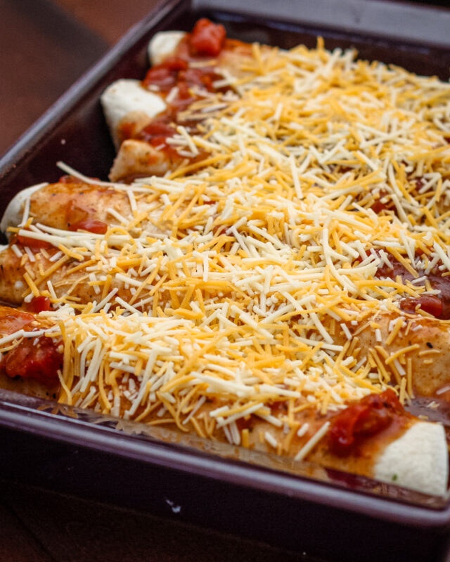 A pan of chicken enchiladas ready to bake