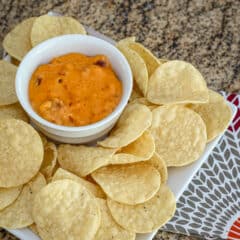 A bowl of chili cheese dip with tortilla chips.