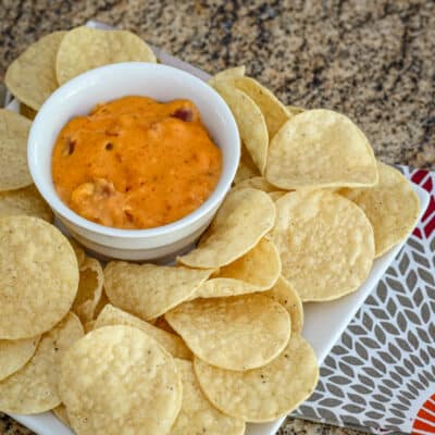 A bowl of chili cheese dip with tortilla chips.