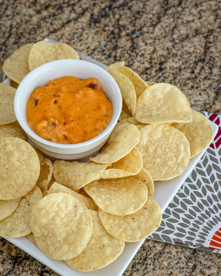 A bowl of chili cheese dip with tortilla chips.