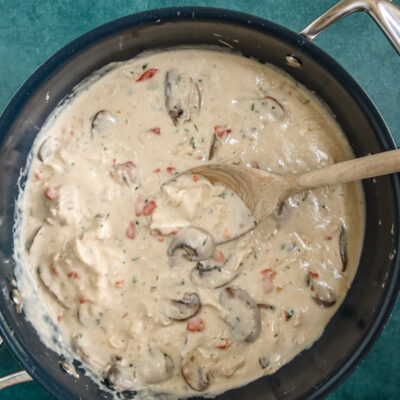 A pan of chicken a la king with a wooden spoon.