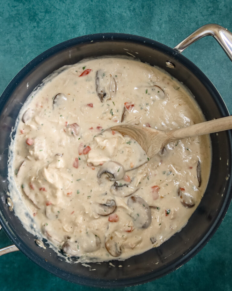 A pan of chicken a la king with a wooden spoon.