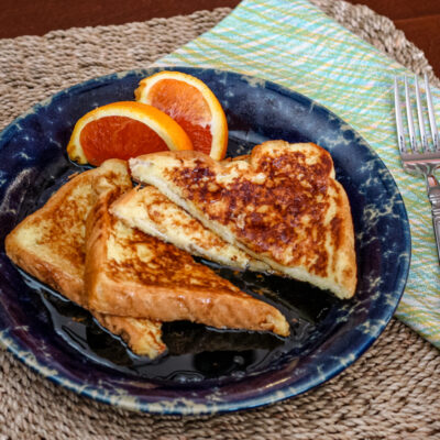 Sliced French toast on a plate with orange wedges on the side.