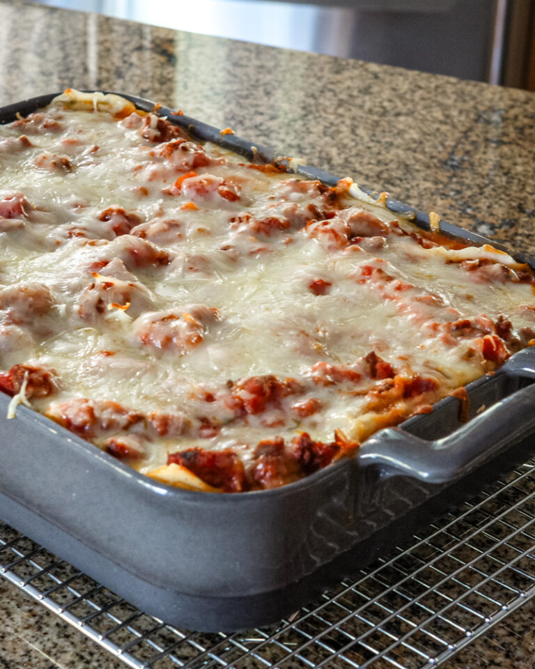 Homemade easy lasagna in a baking dish on a cooling rack.
