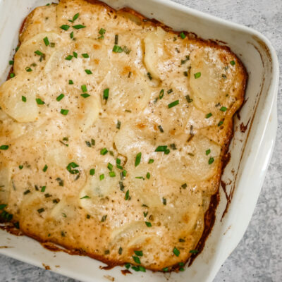 Baking dish with scalloped potatoes ganished with chives.