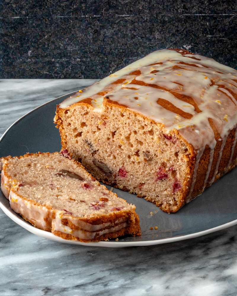 Cranberry sauce bread on a plate with one slice in front.