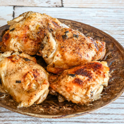 A plate of chicken thighs with lemon and garlic.